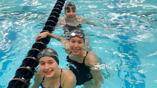 Tres estudiantes están nadando y divirtiéndose en la piscina en el terreno de la Vimy Ridge Academy.