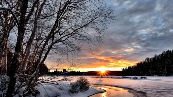 Paisaje invernal con un lago congelado y árboles cubiertos de nieve al atardecer cerca de la Vimy Ridge Academy.