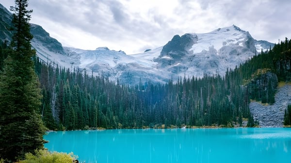 Un tranquilo lago alpino con montañas cubiertas de nieve y bosques perennes en los alrededores de la Vincent Massey Secondary School.