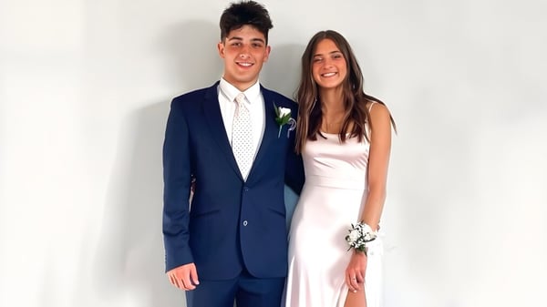 Una joven pareja posa sonriendo frente a un fondo blanco en el campus del Waimea College.