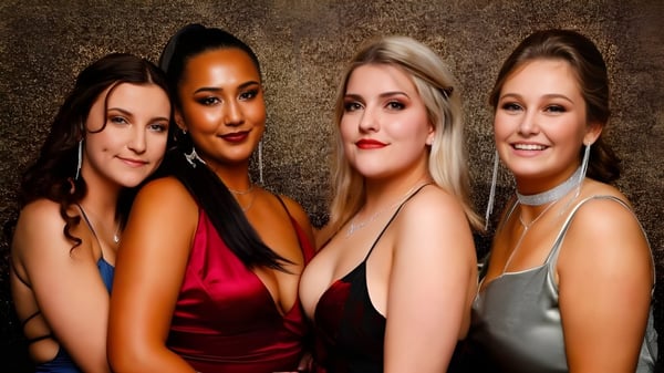 Cuatro mujeres con diferentes apariencias posan juntas frente a un fondo dorado en el campus de Waitakere College.