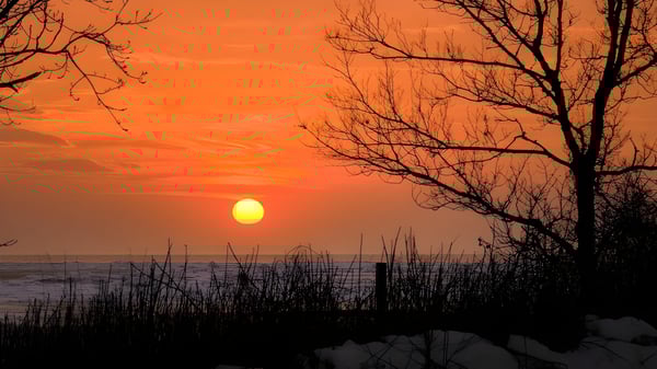 Un atardecer naranja ilumina el cielo sobre el agua cerca del Walkerville Collegiate Institute.