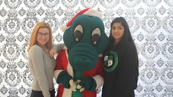 Dos estudiantes posan con una gran figura de cómic verde frente a un papel tapiz estampado en la Walnut Grove Secondary School.