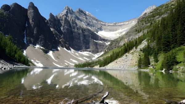Un lago alpino con montañas nevadas y laderas boscosas en el terreno de la Walnut Grove Secondary School.