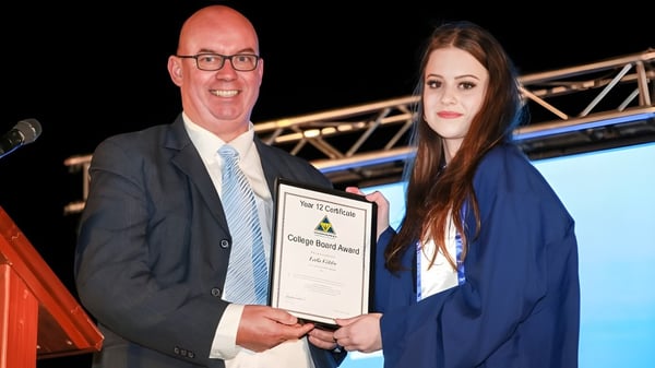 Un hombre y una mujer en ropa formal durante la entrega de un certificado en el campus del Wanneroo Secondary College.