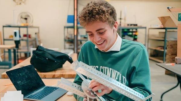 Un estudiante de la Wasatch Academy trabaja sonriendo en un portátil en un taller.