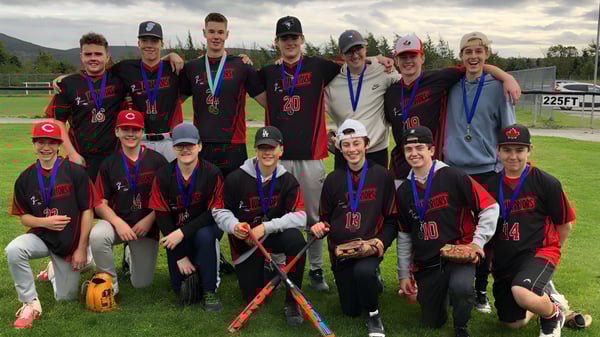 Un grupo de jóvenes deportistas posan en el campo de deportes de la Waterford Valley High School frente a un paisaje montañoso.