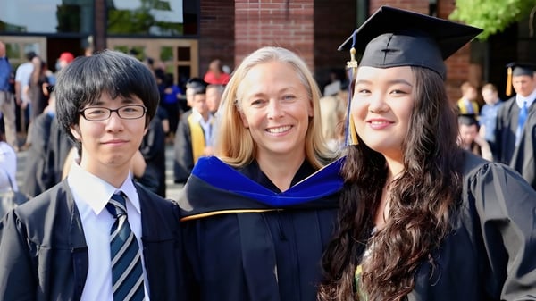 Tres graduadas y graduados del Waterloo Region District School Board están juntos en la ceremonia de graduación.