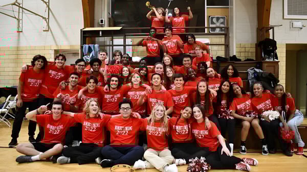 Un grupo de estudiantes de la Wayland Academy con camisetas rojas se reúne en un gimnasio.