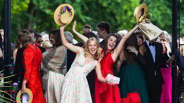 Un grupo de alumnas y alumnos del Wellington College celebran juntos en el recinto escolar frente a un fondo verde.