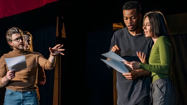 Tres personas de la Wellington Heights Secondary School llevan a cabo una discusión con papeles en la mano.