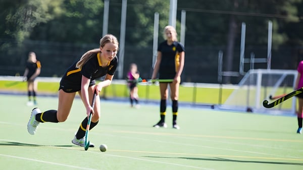 Un grupo de jugadoras de hockey dribla y juega en el campo de césped artificial de la Wellington School.