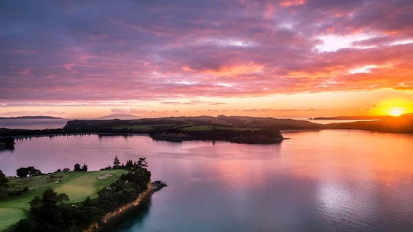 Un atardecer sobre un lago tranquilo con colinas verdes en el terreno del Wentworth College.