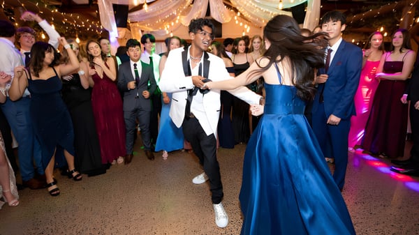 Estudiantes del Wentworth College bailan juntos en un evento festivo en un espacio decorado con iluminación colorida.