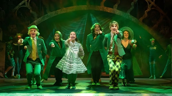 Un grupo de estudiantes del Wesley College presenta una obra de teatro en el escenario frente a un fondo verde.