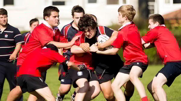 Estudiantes del Wesley College están en uniformes deportivos rojos y negros en un campo de deporte participando en una actividad física.