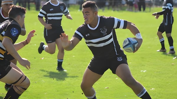 Un grupo de jugadores de rugby en uniformes blanco y negro juega un partido en el campo del Wesley College.