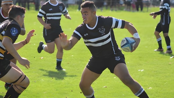 Un grupo de jugadores de rugby en camisetas blanco y negro juega un partido en el campo del Wesley College.