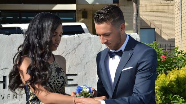 Una pareja está vestida de manera formal frente a un edificio del West Humber Collegiate Institute.