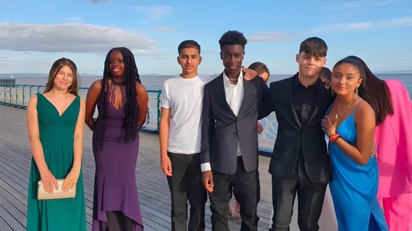 Un grupo de estudiantes está en un muelle de madera sobre el agua en el terreno de la Westbourne School.