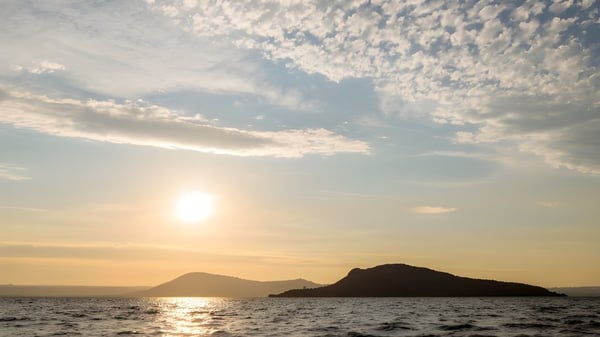 Un tranquilo atardecer con una silueta de montañas y agua reflejante cerca de la Western Heights High School.