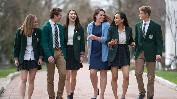 Estudiantes de la Western Reserve Academy caminan juntos por un camino rodeado de árboles.