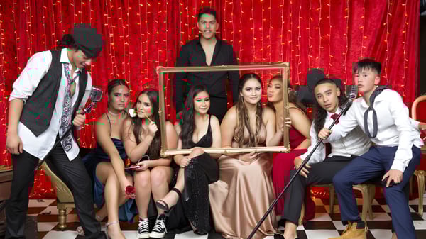 Un grupo de alumnas y alumnos del Western Springs College posan frente a una cortina roja.