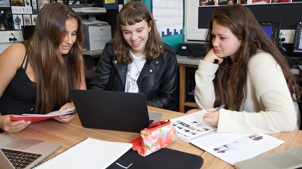 Tres alumnas del Western Springs College trabajan juntas en un laptop en un espacio de trabajo.