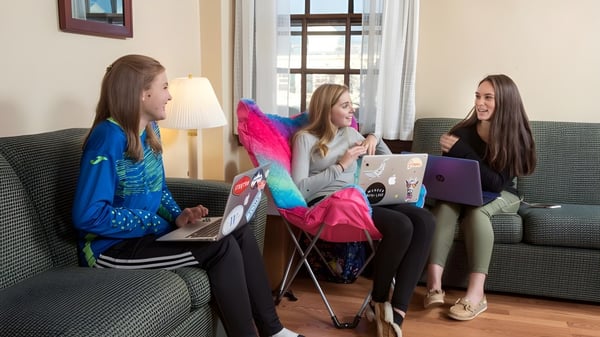 Tres alumnas de la Westover School están sentadas en un sofá y trabajan juntas en portátiles.