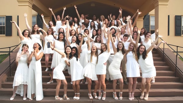 Un gran grupo de jóvenes mujeres de la Westover School está en las escaleras de un edificio y levantan los brazos en una pose de celebración.