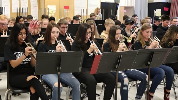 Estudiantes de la Westside Secondary School están sentados en un aula de computación y trabajan en dispositivos electrónicos.