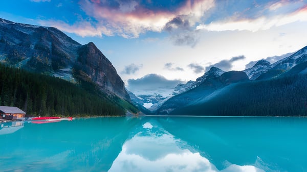Un tranquilo lago turquesa frente a montañas cubiertas de nieve en el terreno de la Westside Secondary School.