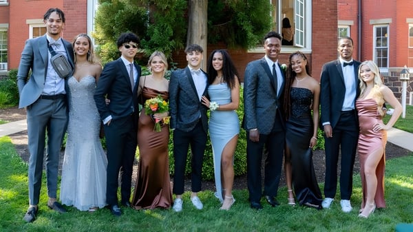 Un grupo de personas posan frente a un edificio de ladrillo en el campus de la Westtown School.