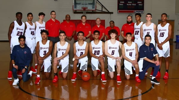 Un grupo de jugadores de baloncesto en camisetas blancas y rojas posan en el campo de baloncesto de la Westview Freedom Academy.