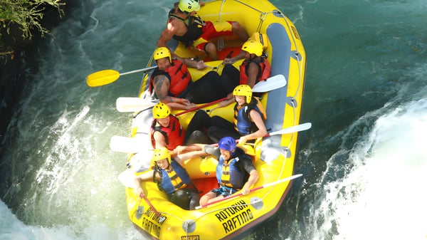 Estudiantes de la Whakatane High School navegan por el río en una balsa amarilla.