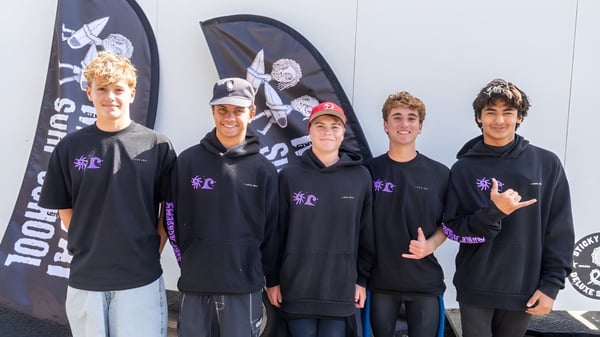 Un grupo de estudiantes de la Whangamata Area School lleva sudaderas negras frente a un fondo de calaveras.