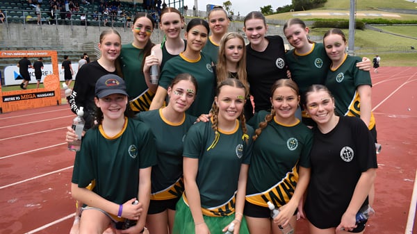 Un grupo de jóvenes atletas posan en camisetas verdes y amarillas en el campo de deportes de Whanganui Girls’ College.