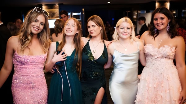 Cinco estudiantes de Whangaparāoa College posan juntas en un evento formal frente a un fondo oscuro.