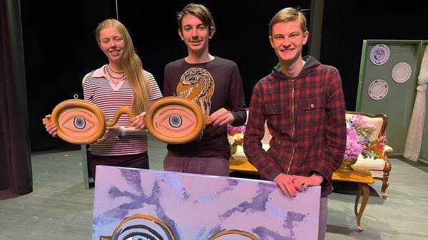 Tres estudiantes de la Whistler Secondary School sostienen objetos redondos coloridos durante una actuación en el escenario.