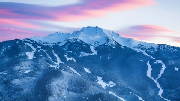 Un impresionante paisaje montañoso con picos cubiertos de nieve frente a un cielo colorido en los alrededores de la Whistler Secondary School.