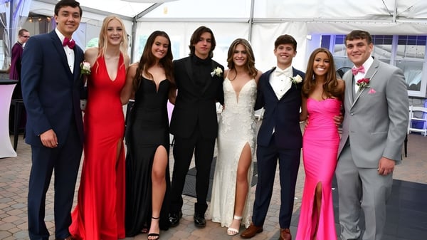 Un grupo de personas bien vestidas posan en un evento en el terreno del Whites Hill State College.