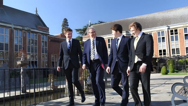 Cuatro hombres con ropa formal están juntos frente a un edificio en el campus de la Whitgift School.