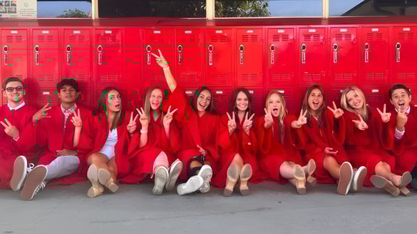 Estudiantes de la Whittier Christian High School están sentadas en uniformes rojos frente a una fila de armarios rojos.