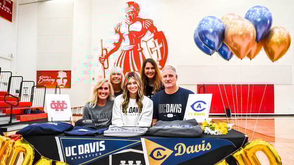 Estudiantes y personal de la Whittier Christian High School están en una mesa de promoción con un gran mural de fondo.