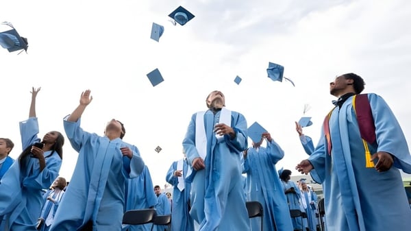 Un grupo de graduados de la Willow Creek Composite High School lanza sus birretes al cielo.