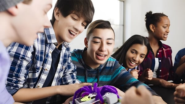 Un grupo de estudiantes de la Willow Creek Composite High School tiene una conversación lúdica en un interior.