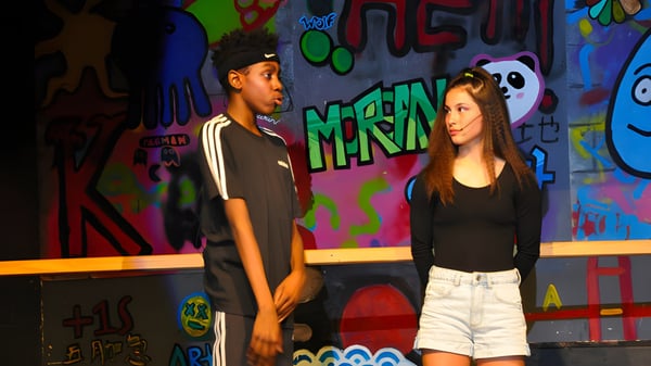 Dos estudiantes de la WillowWood School están frente a una pared de graffiti pintada de colores.