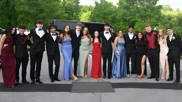 Un grupo de personas vestidas formalmente posan frente a un fondo boscoso en el terreno de la Wilson's Hospital School.