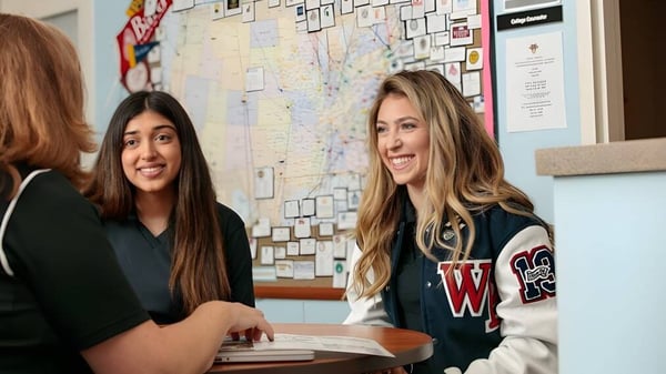 Dos estudiantes se sientan en una mesa en el aula de la Windermere Preparatory School con un fondo de tablón de anuncios.