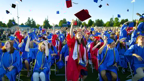 Estudiantes de la Winston Churchill High School llevan birretes y togas en una ceremonia de graduación al aire libre.